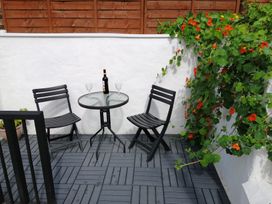 A patio with a table and chairs, wine bottle and glasses at Colliers Cottage in Cinderford