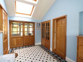 A hallway with skylight wooden doors blue walls and a tiled floor at Studio Cottage in Surlingham near Poringland