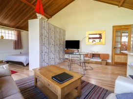 A living area with a wooden coffee table, sofa, and glass dining table with chairs at Studio Cottage in Surlingham near Poringland
