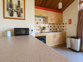 A kitchen with wooden cabinets a microwave utensils kettle and two bins at Studio Cottage in Surlingham near Poringland