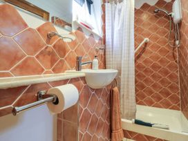 A bathroom with a sink toilet paper holder shower and orange tiles at Studio Cottage in Surlingham near Poringland