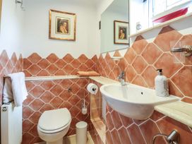 A bathroom with a white toilet and sink orange diamond tiles on walls a framed picture above the toilet and a towel on a radiator at Studio Cottage in Surlingham near Poringland