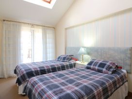A bedroom with two single beds with plaid bedding and a lamp on a bedside table at Studio Cottage in Surlingham near Poringland