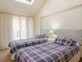 A bedroom with two single beds with plaid bedding a nightstand and a lamp at Studio Cottage in Surlingham near Poringland