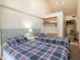 A bedroom with two single beds a bedside table with a lamp and an open wardrobe at Studio Cottage in Surlingham near Poringland