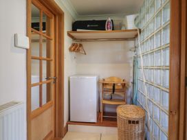 A small utility room with wooden door mini fridge wooden high chair wicker basket and clothes hangers at Studio Cottage Surlingham near Poringland