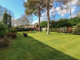 A backyard with grass trees a basketball hoop a slide and swings at Studio Cottage in Surlingham near Poringland