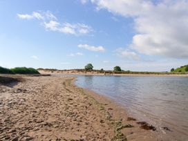 A riverbank with sand and trees at Seafield Granary Alnmouth