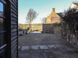 A garden view with a tree and gravel path at Seafield Granary in Alnmouth