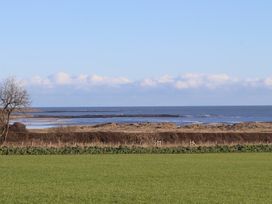 A view of the sea with a grassy field and shoreline at Seafield Granary Alnmouth