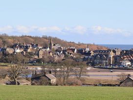 A view of a village with houses and a church near the sea at Seafield Granary in Alnmouth