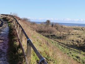 A path along a seaside with a fence and grass at Seafield Granary in Alnmouth