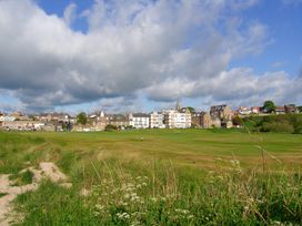 View of a field with houses and cloudy sky at Seafield Coach House in Alnmouth