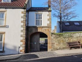An archway entrance with a bench and tree at Seafield Coach House Alnmouth