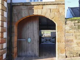A stone archway entrance with a wooden door at Seafield Coach House Alnmouth