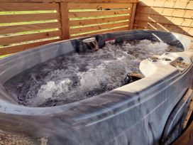 A hot tub with water in an outdoor area at Fir Tree Shepherd's Hut Llanon