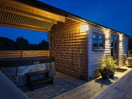 An outdoor terrace with a hot tub and a flower pot at Fir Tree Shepherd's Hut in Llanon