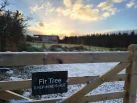 A shepherd's hut visible beyond a wooden gate at Fir Tree Shepherd's Hut in Llanon