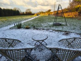 A garden with chairs and a table covered in snow at Fir Tree Shepherd's Hut in Llanon