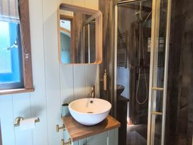 A bathroom with a sink and shower at Fir Tree Shepherd's Hut in Llanon