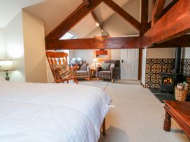 A bedroom with a bed, lamp, chair, and wood stove at Coldbeck Cottage in Ravenstonedale