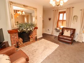 A living room with a fireplace and a mirror at Beckside Cottage in Penrith