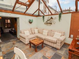 A conservatory with a corner sofa and coffee table at Beckside Cottage in Penrith