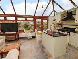 A conservatory with a kitchen island and seating area at Beckside Cottage in Penrith