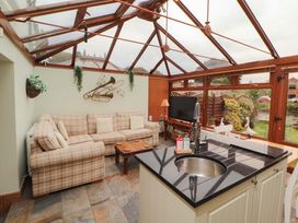 A conservatory with a sofa and a kitchen island at Beckside Cottage in Penrith