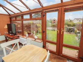 A conservatory with a television and a table at Beckside Cottage in Penrith