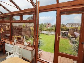 A conservatory with glass doors viewing a garden at Beckside Cottage Penrith