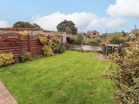 A garden with grass, fence, table, and chairs at Beckside Cottage, Penrith