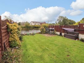 A garden with a table and chairs near water at Beckside Cottage, Penrith