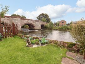A garden with a river and a bridge at Beckside Cottage in Penrith