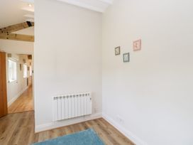 A hallway with a white wall radiator three small framed pictures on the wall and a blue rug on the wooden floor at South Barn Cottage in Hatford near Stanford In The Vale