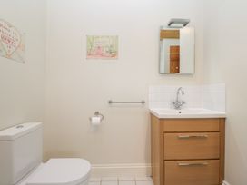 A bathroom with a toilet a wooden sink cabinet a mirror and wall art at South Barn Cottage in Hatford near Stanford In The Vale