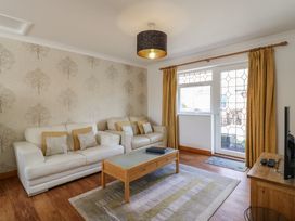 A sitting room with two white sofas a wooden coffee table and a rug by Garden Cottage in Surlingham near Poringland