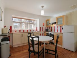 A kitchen with a round table and four chairs a stove a refrigerator and cabinets at Garden Cottage in Surlingham near Poringland