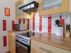 A kitchen countertop with a stove microwave utensil holder and knives at Garden Cottage Surlingham near Poringland