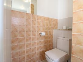 A bathroom with a toilet and a roll of toilet paper on the wall at Garden Cottage in Surlingham near Poringland