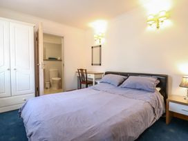 A bedroom with a bed a desk and chair a wardrobe and an en suite bathroom at Garden Cottage in Surlingham near Poringland