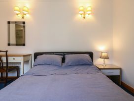 A bedroom with a bed with blue bedding a nightstand with a lamp a desk with a chair and a mirror on the wall at Garden Cottage in Surlingham near Poringland