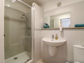 A bathroom with a shower cubicle a sink with soap a toilet and a mirror at Garden Cottage in Surlingham near Poringland