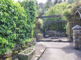 An outdoor garden area with stone walls pathways and greenery at Wayside Farm Dairy Cottage in Cloughton near Burniston