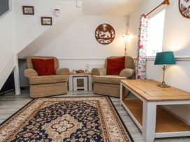 A sitting area with two armchairs with red cushions a patterned rug and a wooden coffee table with lamp at Wayside Farm Dairy Cottage Cloughton near Burniston