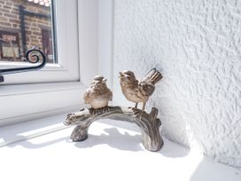 Two bird figurines perched on a branch decoration on a windowsill