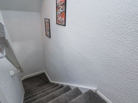 A staircase with grey carpet and two framed pictures on a white textured wall at Wayside Farm Dairy Cottage in Cloughton near Burniston