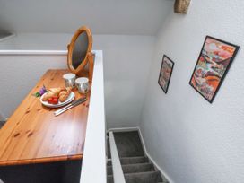 A wooden desk with a round mirror mugs croissants strawberries and cutlery next to a staircase with colorful framed pictures on the wall at Wayside Farm Dairy Cottage Cloughton near Burniston