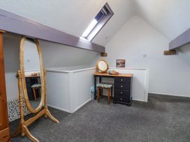 An attic space with a full-length mirror wooden dressing table and a stool under a skylight at Wayside Farm Dairy Cottage in Cloughton near Burniston