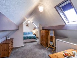 A bedroom with sloped ceilings a bed a wooden wardrobe a standing mirror a chest of drawers and a table with breakfast at Wayside Farm Dairy Cottage Cloughton near Burniston